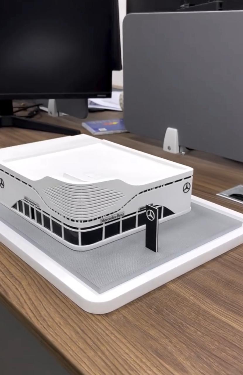 White automotive showroom scale model with curved facade on a rectangular base